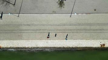 Luftdrohnenansicht von Menschen, die neben dem Fluss in der Stadt Lissabon, Portugal, laufen, joggen und entspannen. digitale Nomaden. weltweit führende Metropole am Meer. Alltag. video