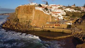 Aerial drone view of Azenhas do Mar, Portugal. Natural pool in the ocean, next to the cliff and a seaside village during sunset. Best destinations in the world. Most visited places. Holidays.