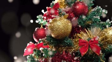 nevando en un pino decorado con navidad, nieve cayendo a cámara lenta en invierno, adornos de cerca video