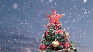 nieve en el pino decorado con navidad durante la noche de la víspera de navidad. invierno nevando a cámara lenta. video