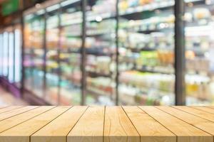 Empty wood table top with supermarket grocery store aisle and shelves blurred background photo