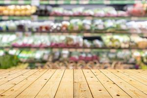 Wood table top with vegetables on grocery store shelves blurred background photo