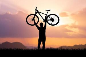 Man holds a bicycle on top of a mountain. concept of success and victory