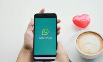 chiang mai, tailandia - 23 de agosto de 2020 - una mujer sostiene un teléfono móvil huawei con la aplicación whatsapp en la pantalla en una cafetería. WhatsApp se utiliza para el envío de mensajes de texto y llamadas de voz. foto