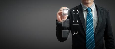 a businessman in a suit holding a pen touching the virtual screen on the happy Smiley face icon to give satisfaction in service.rating very impressed.Customer service and Satisfaction concept photo