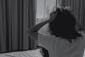 World Mental Health Day concept. Rear view of angry woman put hand on head and pulling hair. Mental illness woman sit on bed in bedroom. Woman with mental health problems. Stressed and nervous person. photo