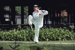 joven practicando la espada tradicional de tai chi, tai ji en el parque para el concepto saludable y tradicional de artes marciales chinas sobre fondo natural. foto