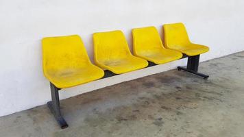 cuatro asientos amarillos de fibra o plástico colocados en el suelo con fondo de hormigón blanco. concepto de objeto y mobiliario de diseño. foto