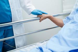 Asian elder senior woman patient holding bed rail while lie down with hope waiting her family in hospital. photo