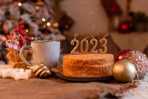 homemade honey cake in the kitchen with candles 2023. Cozy New Year at home. Merry Christmas. High quality photo