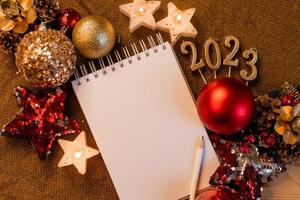 cuaderno con páginas en blanco con juguetes, regalos y números de año nuevo 2023. planes y sueños para el nuevo año, espacio para texto foto