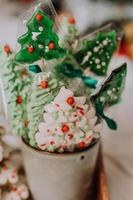 dulces navideños, pan de jengibre pintado con glaseado, piruletas y merengues en forma de árboles de navidad y mandarinas en una bonita bandeja. tortas caseras deliciosa comida para las vacaciones de invierno foto