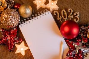 cuaderno con páginas en blanco con juguetes, regalos y números de año nuevo 2023. planes y sueños para el nuevo año, espacio para texto foto