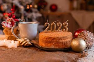 homemade honey cake in the kitchen with candles 2023. Cozy New Year at home. Merry Christmas. High quality photo