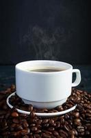 Cup of coffee with coffee beans on dark background. Mug of hot drink coffee photo