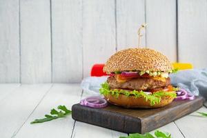 Homemade classic hamburger with beef cutlet, cheese, lettuce and tomato on wooden background