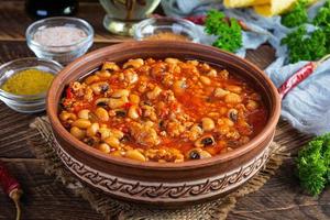 Chili con carne in a bowl on wooden background. Mexican cuisine photo