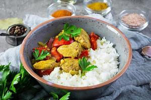 Spicy chicken curry with rice. Curry sauce with chicken and rice on gray background photo