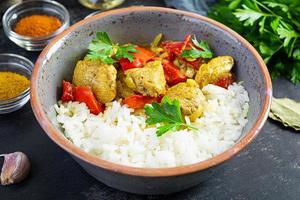 Spicy chicken curry with rice. Curry sauce with chicken and rice on dark background photo