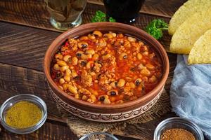 Chili con carne in a bowl on wooden background. Mexican cuisine