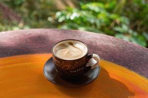 Cup with hot milk coffee on a colorful wooden table in a cafe. Dalat, Vietnam. photo