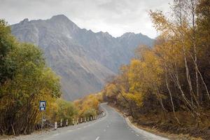 Empty road between in mountains between autumn forest. photo