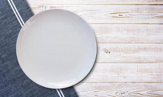 Empty white plate and napkin on light grey table, flat lay photo