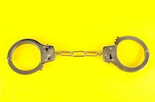 Handcuffs on yellow background photo