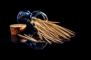 palillos de madera de bambú en frasco de vidrio, copa de vino. en cubo. palillos de dientes sobre fondo negro. palillos de vista frontal, caídos de la mano, lugar para texto, foto