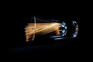 bamboo wooden toothpicks in glass jar, wine glass. in bucket. toothpicks on black background. front view toothpicks, dropped from hand, place for text, photo