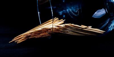 bamboo wooden toothpicks in glass jar, wine glass. in bucket. toothpicks on black background. front view toothpicks, dropped from hand, place for text, photo