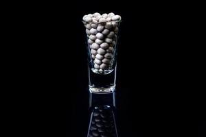 raw white beans in glass jar, wine glass. in bucket. raw white beans on black background. front view raw white beans, dropped from hand, isolated photo