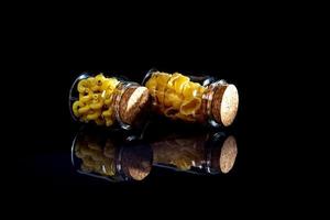 raw pasta in glass jar, wine glass. in bucket. raw pasta on black background. front view raw pasta, dropped from hand, place for text, yellow long spaghetti straws, photo