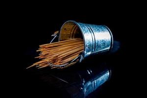 palillos de madera de bambú en frasco de vidrio, copa de vino. en cubo. palillos de dientes sobre fondo negro. palillos de vista frontal, caídos de la mano, lugar para texto, foto