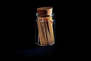 bamboo wooden toothpicks in glass jar, wine glass. in bucket. toothpicks on black background. front view toothpicks, dropped from hand, place for text, photo