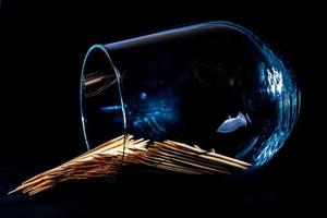 bamboo wooden toothpicks in glass jar, wine glass. in bucket. toothpicks on black background. front view toothpicks, dropped from hand, place for text, photo