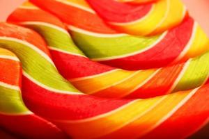 Lollipop multicolored close-up as background texture on pieces on pink background. photo