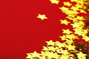 A scattering of Golden stars on red background. The concept of greeting cards, headlines and web site.