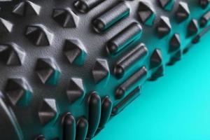 Black bumpy foam massage roller, body roller on blue background. F photo