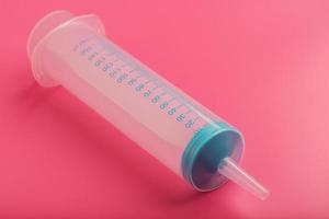 Medical syringe on cyanide, pink background close-up, copy space. The concept of minimalism. photo