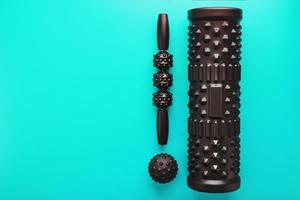 A set of black bumpy foam massage rollers, body rollers, rubber balls on a blue background. photo