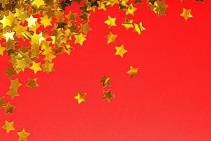 una dispersión de estrellas doradas sobre un fondo rojo. tarjetas de felicitación, titulares y concepto de sitio web. foto