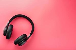 Black wireless headphones on a pink background. Overhead, isolated professional-grade headphones for DJs and musicians photo