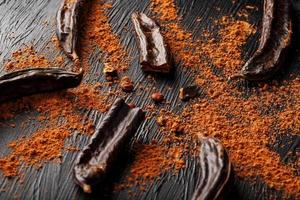Carob carob fruit with powder on black background. Blast the Sweet powder from the pulp of the pods. photo