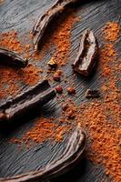 Carob carob fruit with powder on black background. Blast the Sweet powder from the pulp of the pods. photo