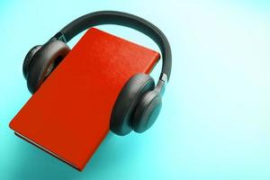 Headphones are worn on a book in a red hardcover on a blue background, top view. photo