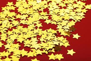 una dispersión de estrellas doradas sobre fondo rojo. el concepto de tarjetas de felicitación, titulares y sitio web. foto