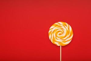 Colorful round Lollipop, on red background. Minimal concept with copy space. photo