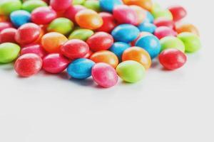 un arco iris de color de caramelos multicolores de primer plano, gragea de glaseado multicolor sobre un fondo blanco foto