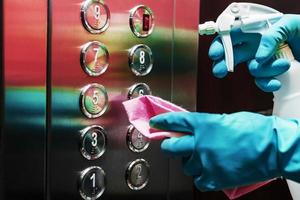 Disinfection and hygienic care using alcohol spray on the elevator button. photo